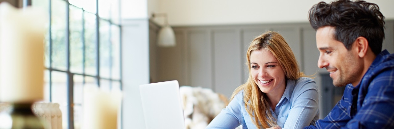 Shot of a happy young couple browsing the internet together at their kitchen table