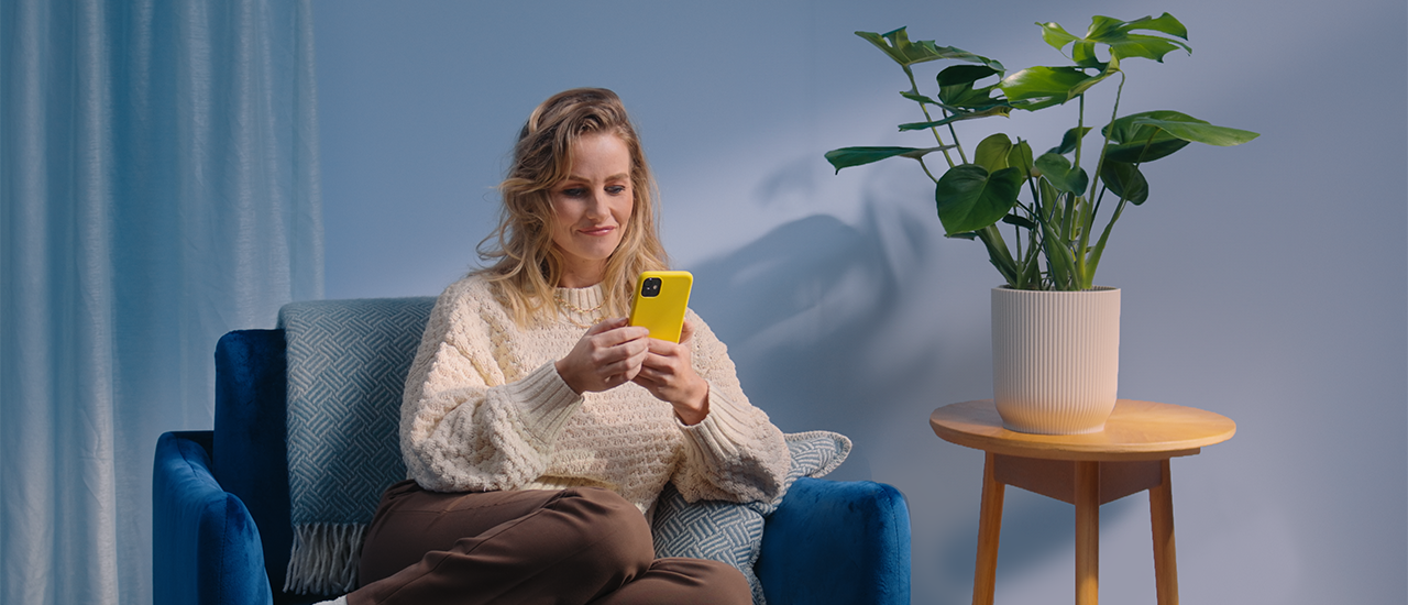 Vrouw zit in fauteuil op mobiele telefoon