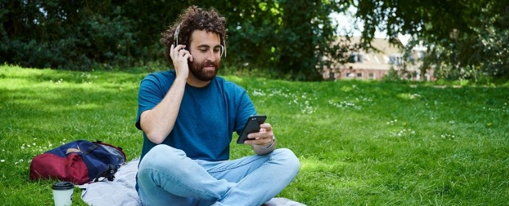Man zit in het gras met een koptelefoon