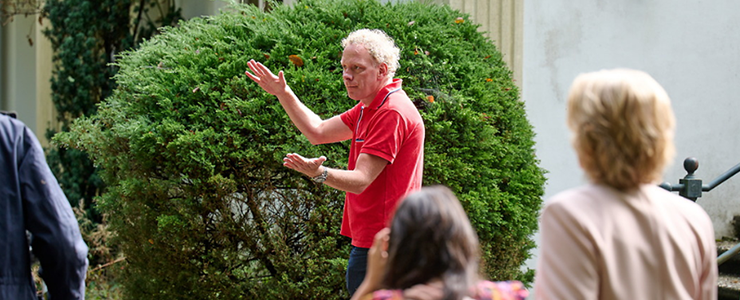 Man in rood shirt spreekt voor publiek