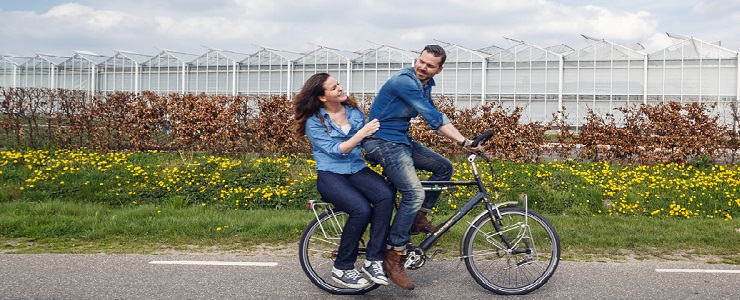 Man en vrouw op een fiets in kassengebied