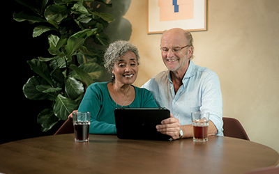 Man en vrouw zitten aan tafel en kijken samen op een tablet